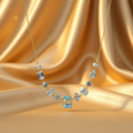 Crystal Bloom Icy Blue Gemstone Necklace by Velora Luxe on gold satin background