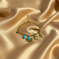 Turquoise Charm Bracelet by Velora Luxe on gold satin background